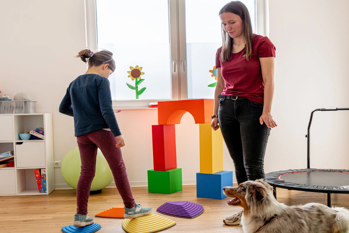 Kind absolviert eine Bewegungsübung mit einem Therapiehund im Rahmen der tiergestützten Ergotherapie