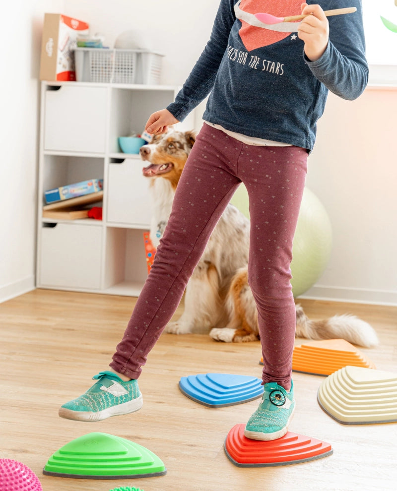 Kind bei einer Bewegungsübung mit bunten Balanceelementen zur Förderung von Gleichgewicht Koordination und motorischen Fähigkeiten in der Kindertherapie