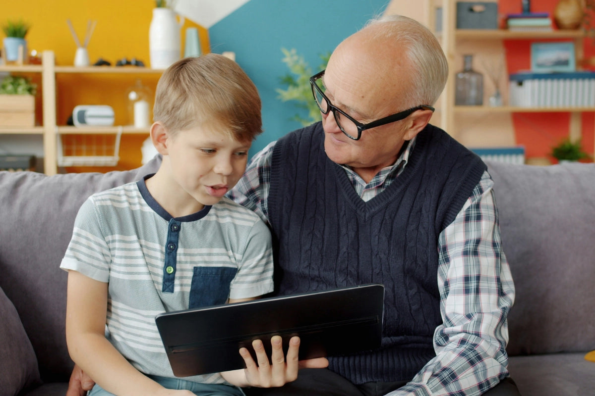 Kind und älterer Mann im Gespräch mit einem Tablet als Symbol für Kommunikation in der Logopädie